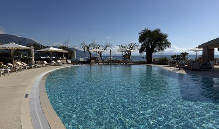 A resort infinity pool edged with sun loungers, looking out to hills