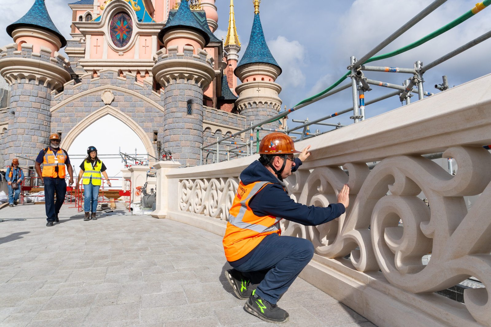 A worker checking the carved stone balustrade on the bridge in front of Sleeping Beauty Castle