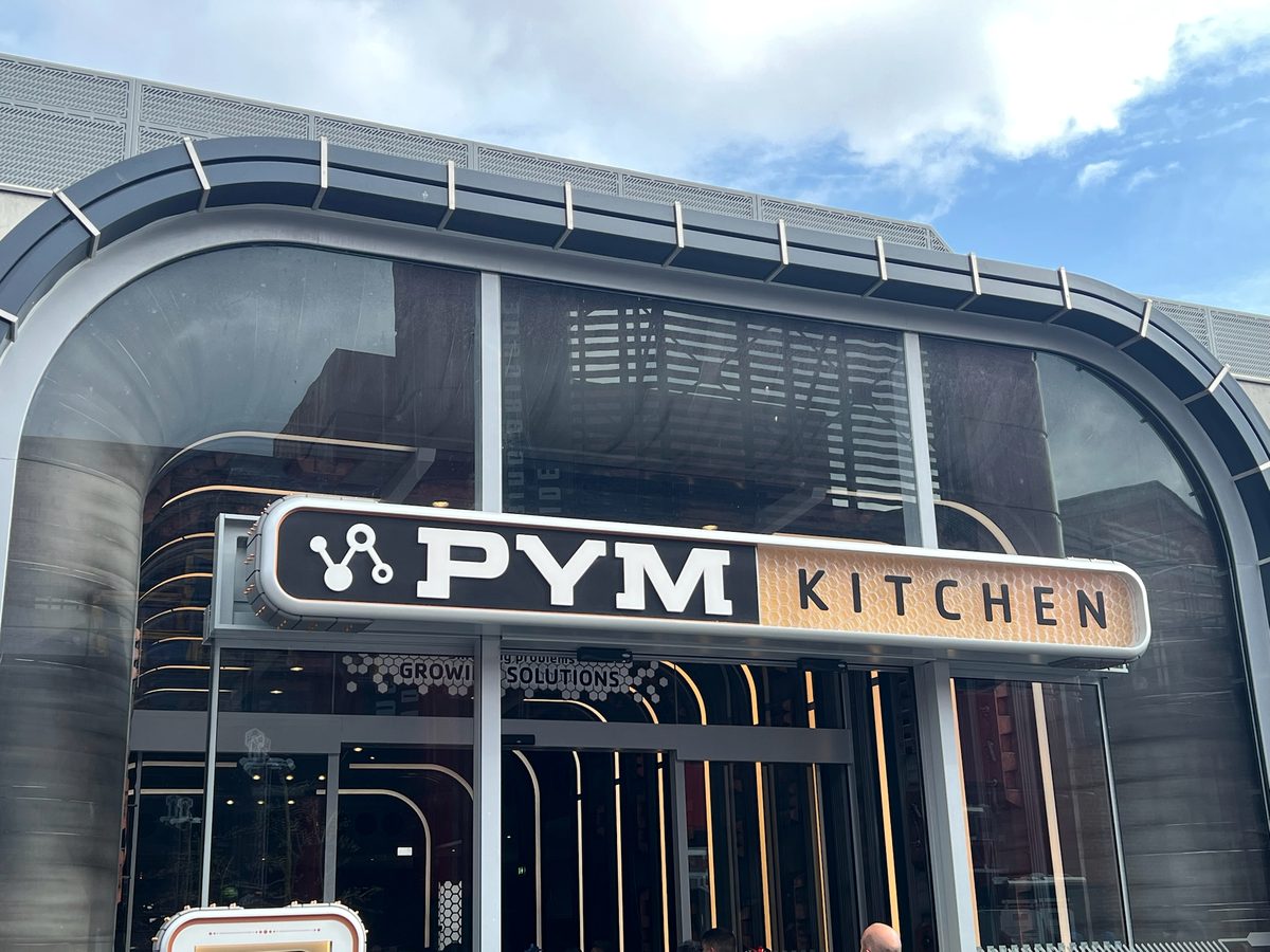 The PYM Kitchen sign over the glass front of the buffet restaurant in Avengers Campus