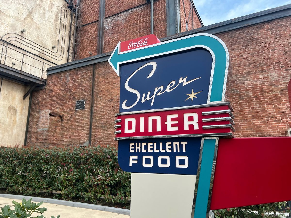 The retro Super Diner arrow sign against a brick wall, with Excellent Food lettering below