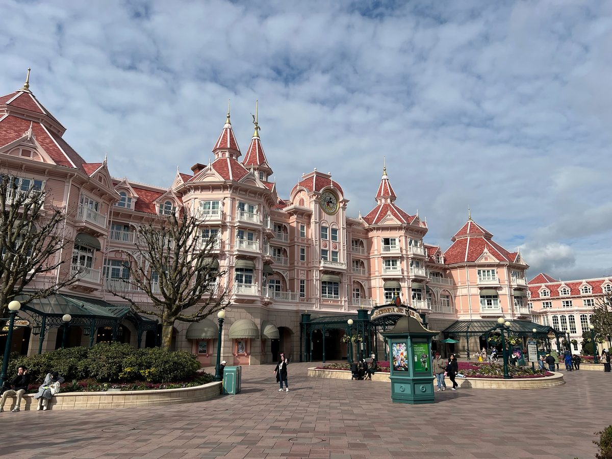 The pink turrets and clock tower of the Disneyland Hotel seen across the entrance plaza