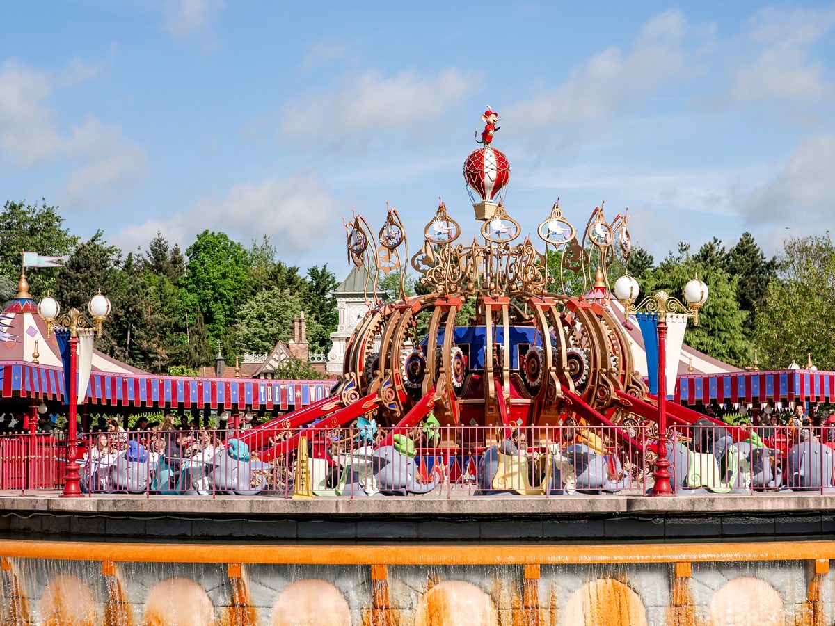 The Dumbo the Flying Elephant ride turning above its fountain wall, every elephant filled