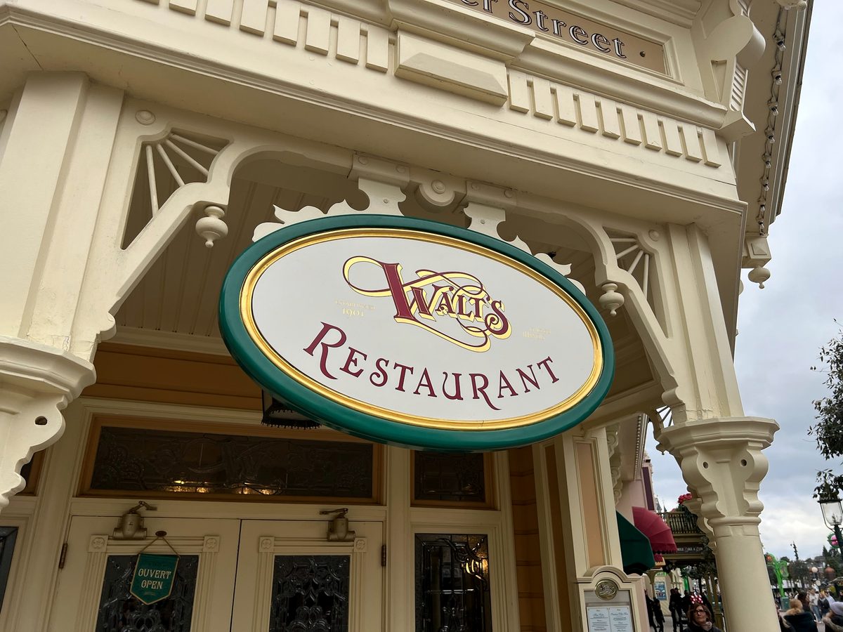 The oval Walt's Restaurant sign hanging over the doors on Main Street, U.S.A.