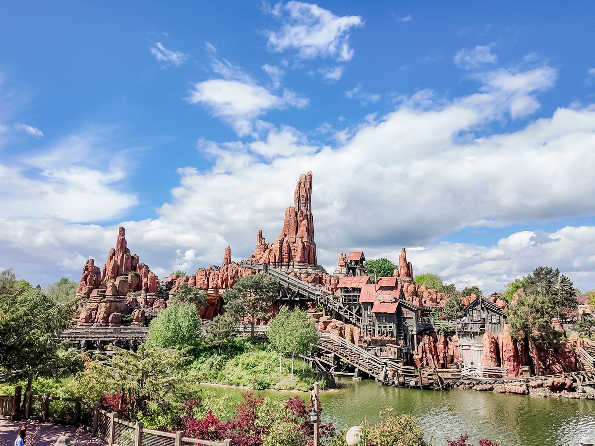Big Thunder Mountain, a mine-train ride built into a red rock formation, seen across the water in Frontierland at Disneyland Park