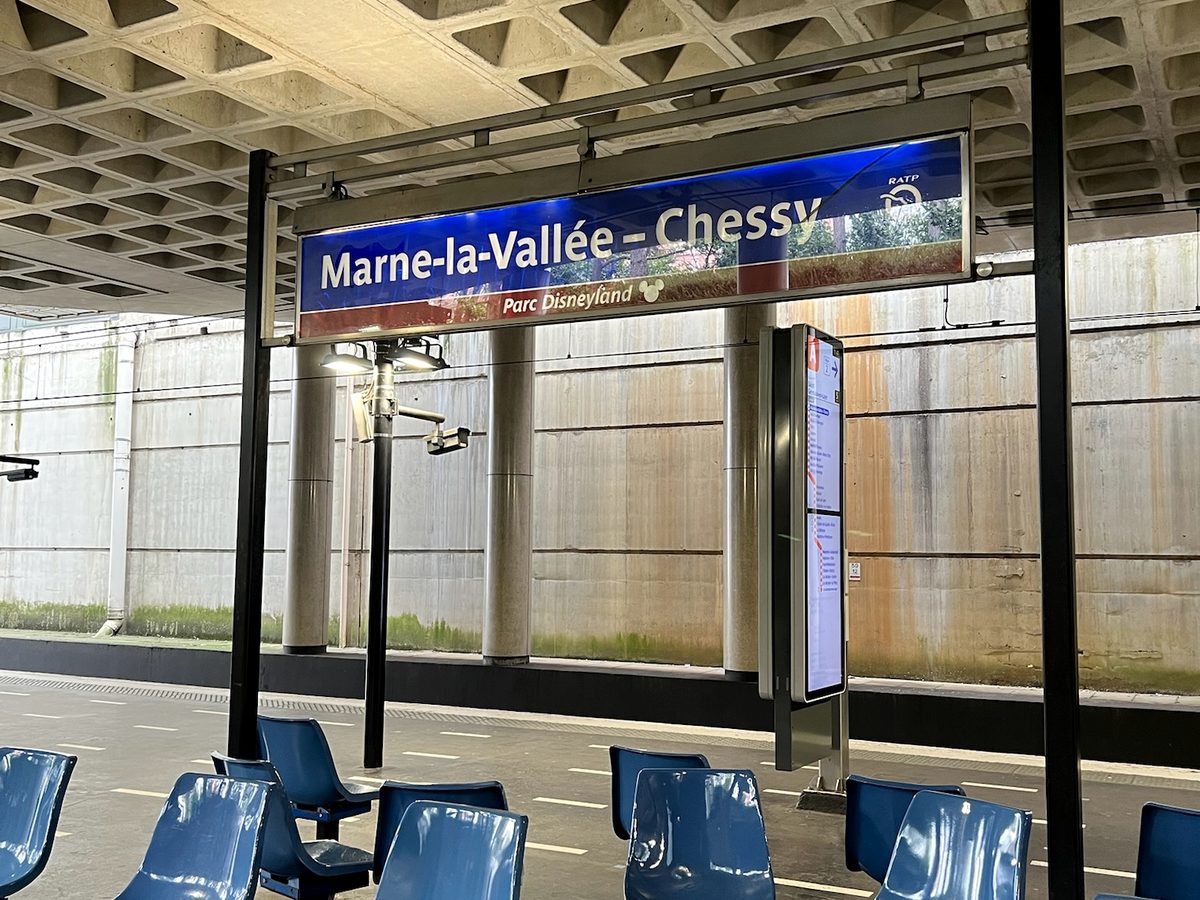 The blue Marne-la-Vallée-Chessy platform sign, subtitled Parc Disneyland, above rows of blue platform seats
