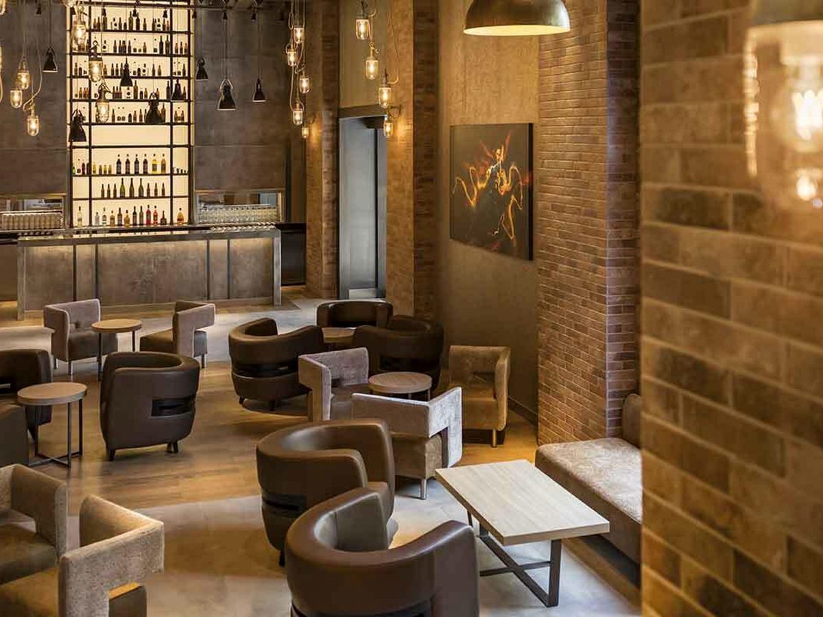 The Bleecker Street Lounge, brick walls, brown leather chairs and a lit bar back at Disney Hotel New York – The Art of Marvel
