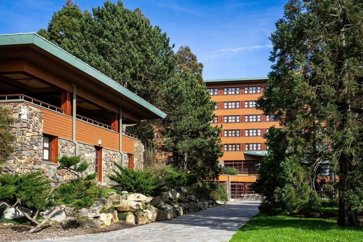 The timber-and-stone main building of Disney Sequoia Lodge rising above the trees on the shore of Lake Disney