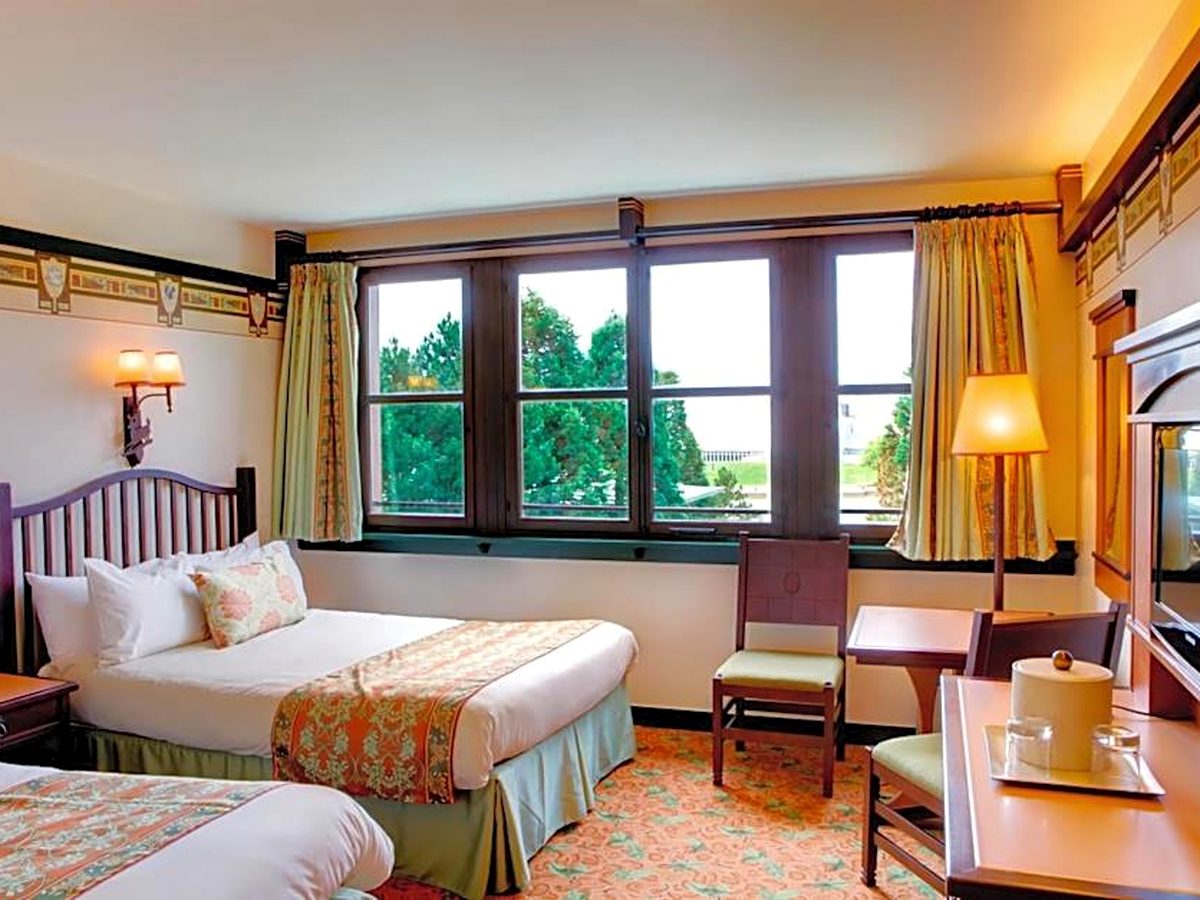 A standard room at Disney Sequoia Lodge, a double bed beneath a woodland frieze with big windows onto the trees