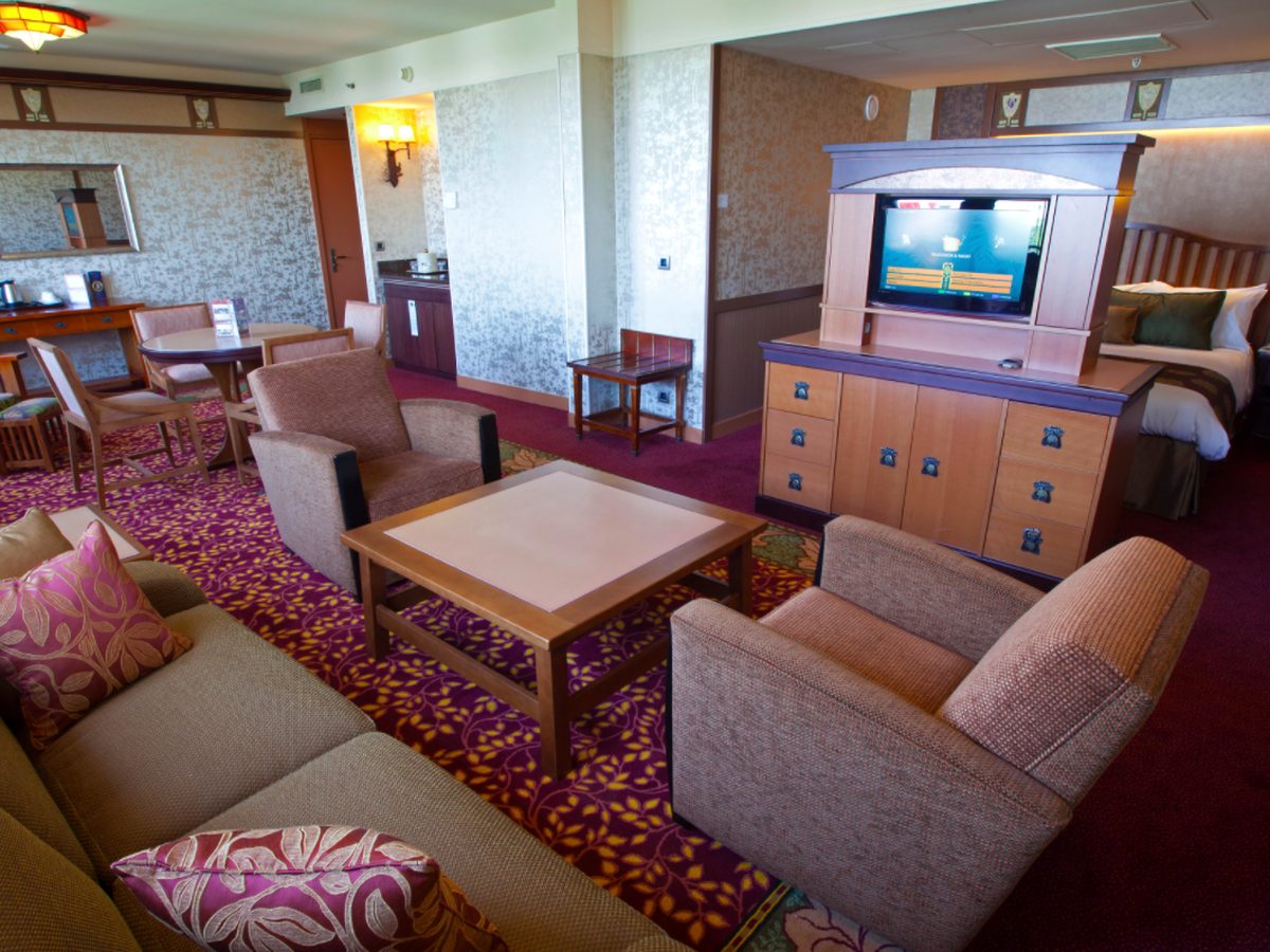 The living area of the Golden Forest Club Suite at Disney Sequoia Lodge, sofas and armchairs around a low table with a television cabinet