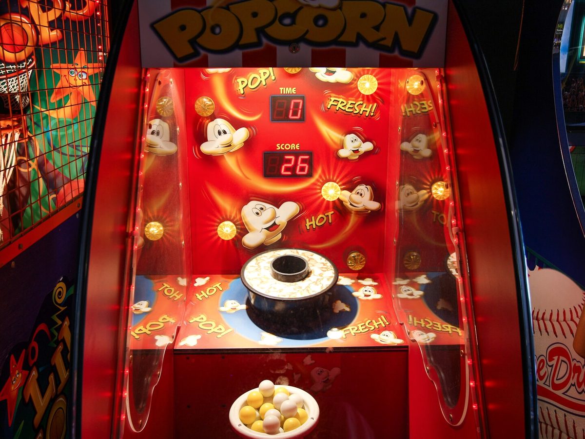 A popcorn-themed basketball arcade machine glowing red and gold inside Lafferty Place Arcade