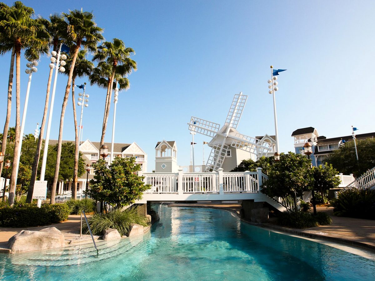 A turquoise stretch of Stormalong Bay with rockwork, a white footbridge and palm trees against a blue sky