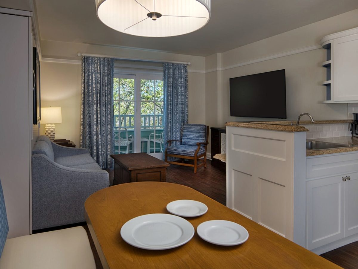 A Beach Club Villas dining table and kitchenette with white cabinets, a sink, a dishwasher and a coffee maker