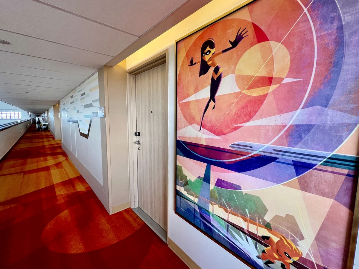 A corridor at Disney's Contemporary Resort with a red and orange retro carpet and a large geometric Incredibles artwork of Violet beside a guest-room door