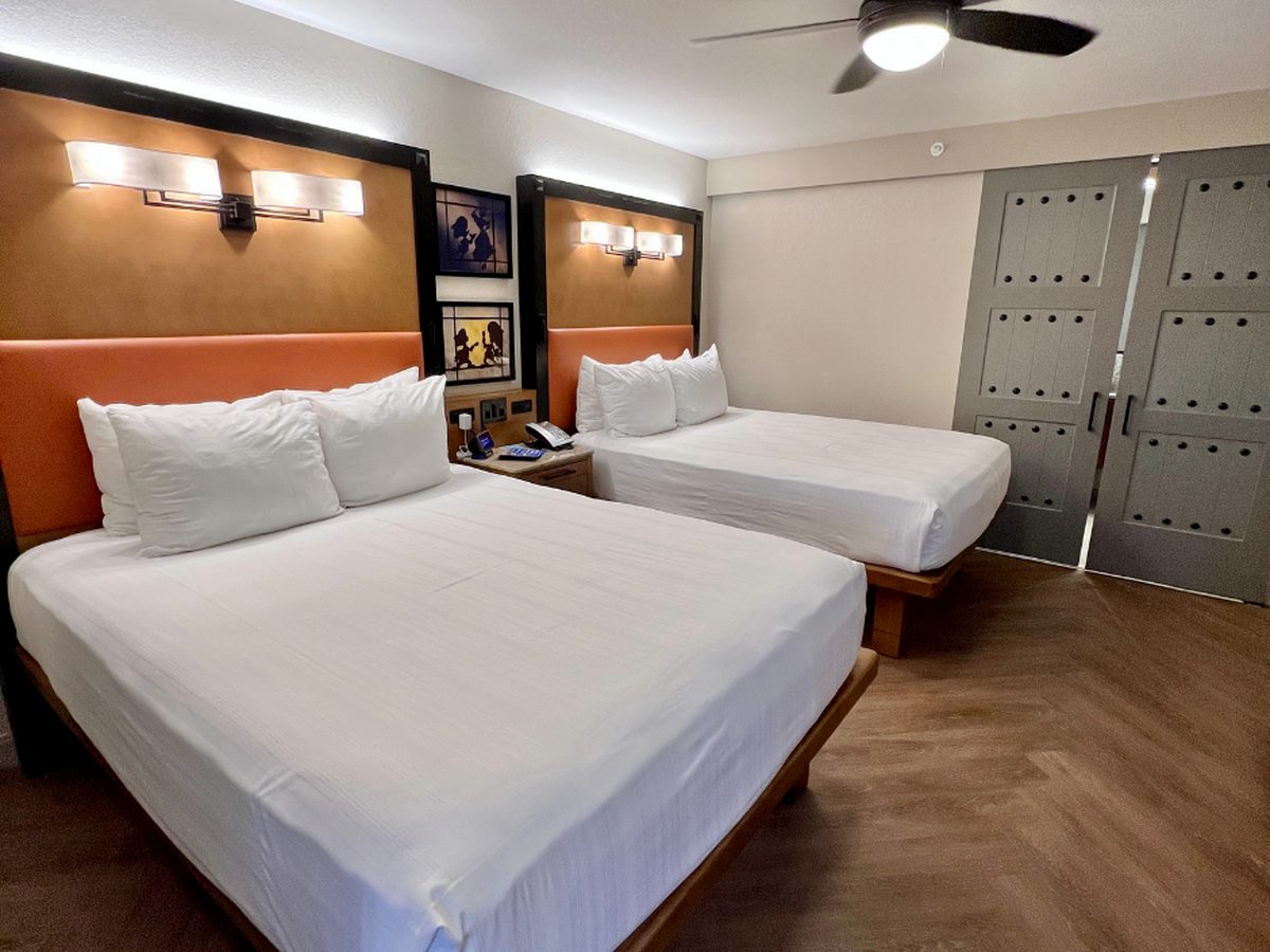 A village room at Disney's Coronado Springs Resort with two queen beds, orange leather headboards and grey sliding doors to the bathroom