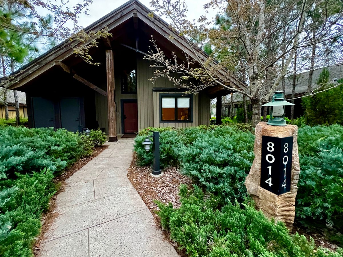 The front path to Cascade Cabin 8014 at Disney's Wilderness Lodge, a timber cabin among pines with a stone number post and lantern