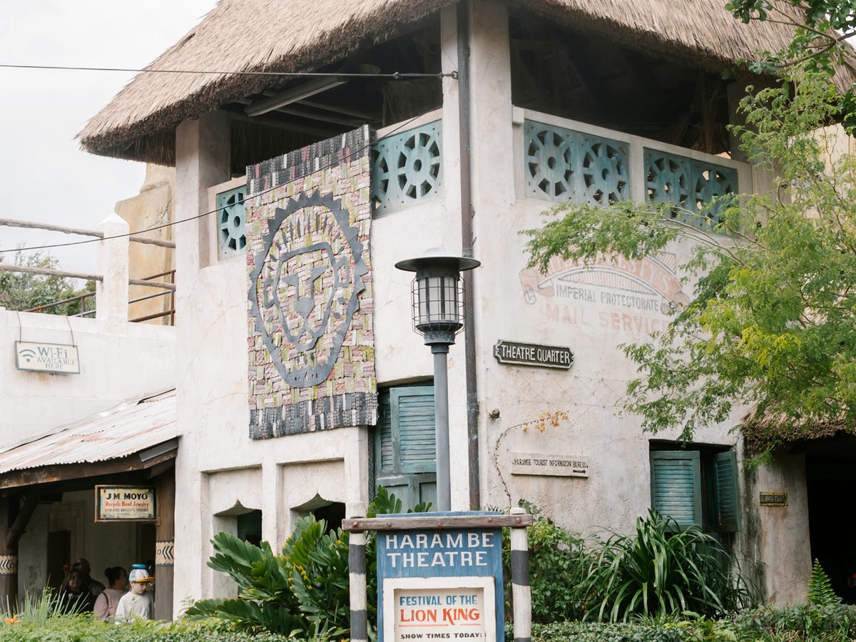 The Harambe Theatre building at Animal Kingdom, a thatched-roofed theatre with a lion mosaic banner and the Festival of the Lion King sign outside