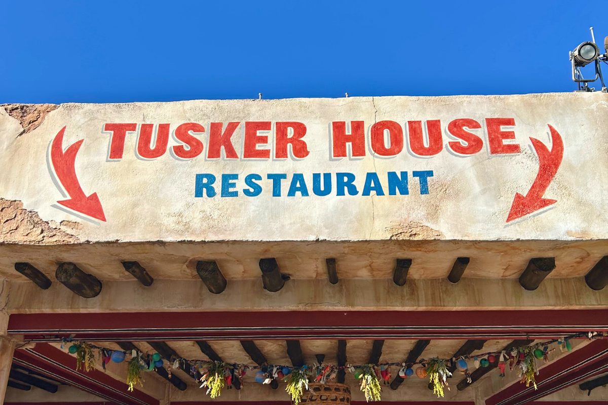 The painted Tusker House Restaurant sign with red arrows above the entrance in the Harambe village area of Animal Kingdom