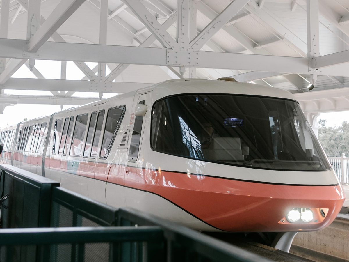 A Walt Disney World monorail with an orange stripe waiting at a station platform