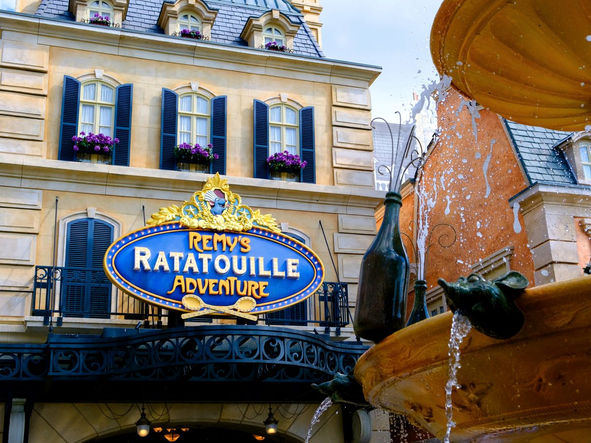 The Remy's Ratatouille Adventure sign above the ride entrance in the France pavilion, with the rat-topped fountain in front