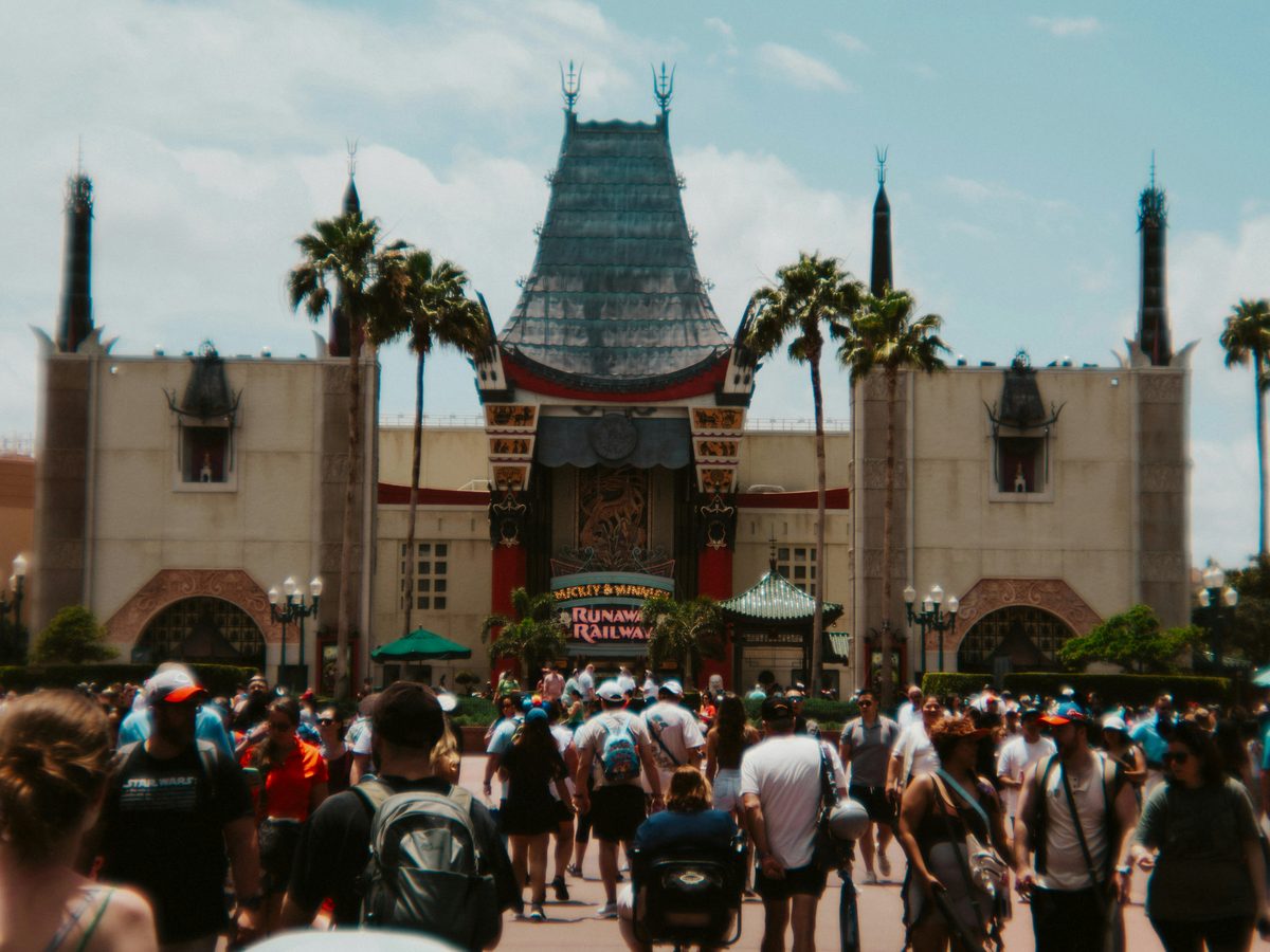 The Chinese Theatre at the end of Hollywood Boulevard, flanked by palm trees, with crowds walking towards it