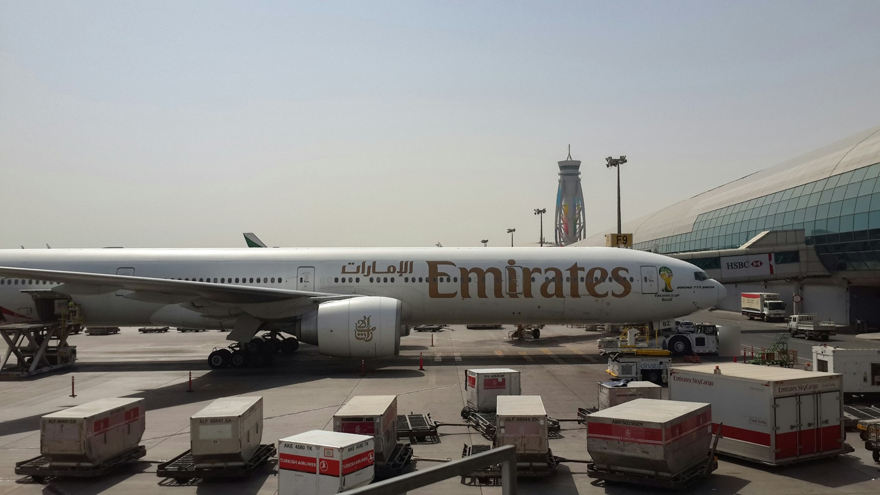 An Emirates Boeing 777 parked beside a terminal at Dubai International Airport