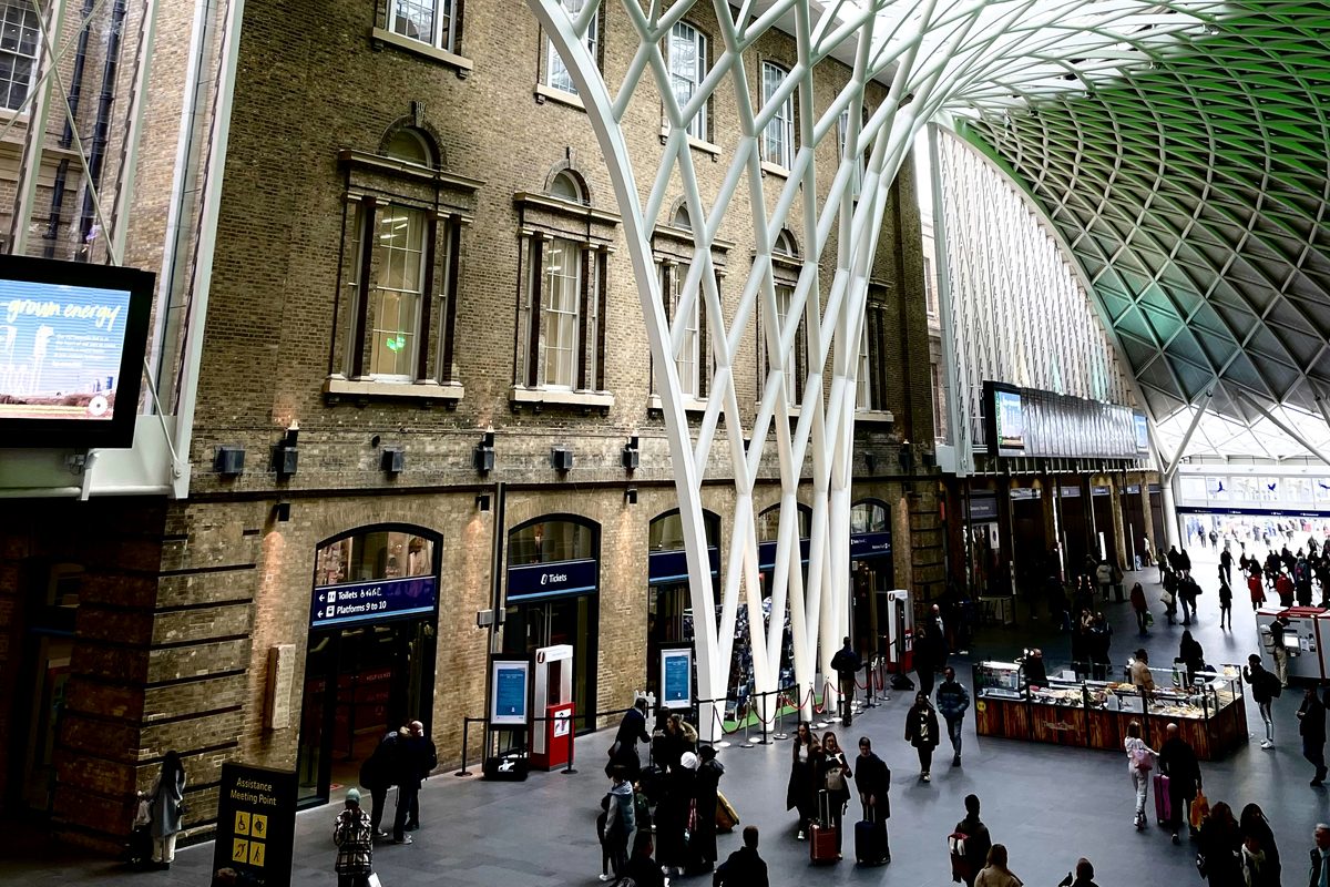 People walking beneath the white branching roof in King's Cross station.