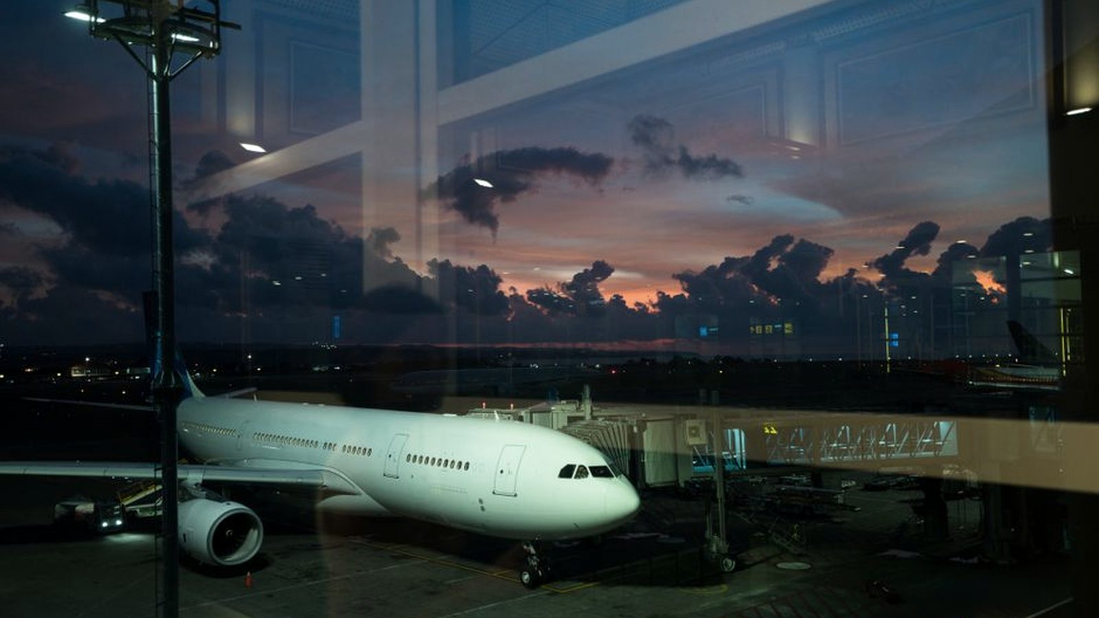 An aircraft parked at an airport gate at dusk
