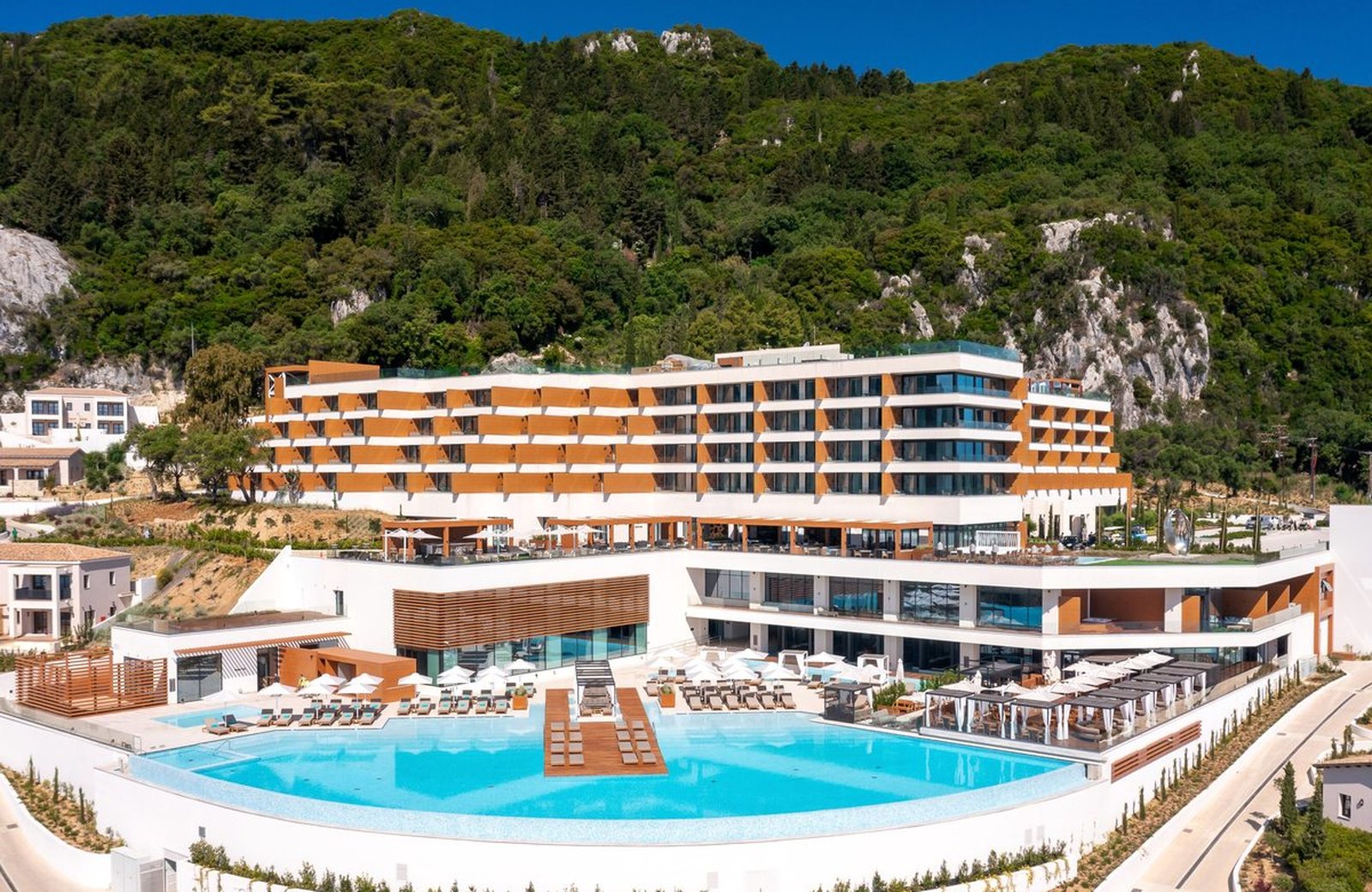 Angsana Corfu Resort & Spa: a terraced five-star resort on a green hillside above Benitses, with the main building and the large infinity pool above the Ionian Sea.