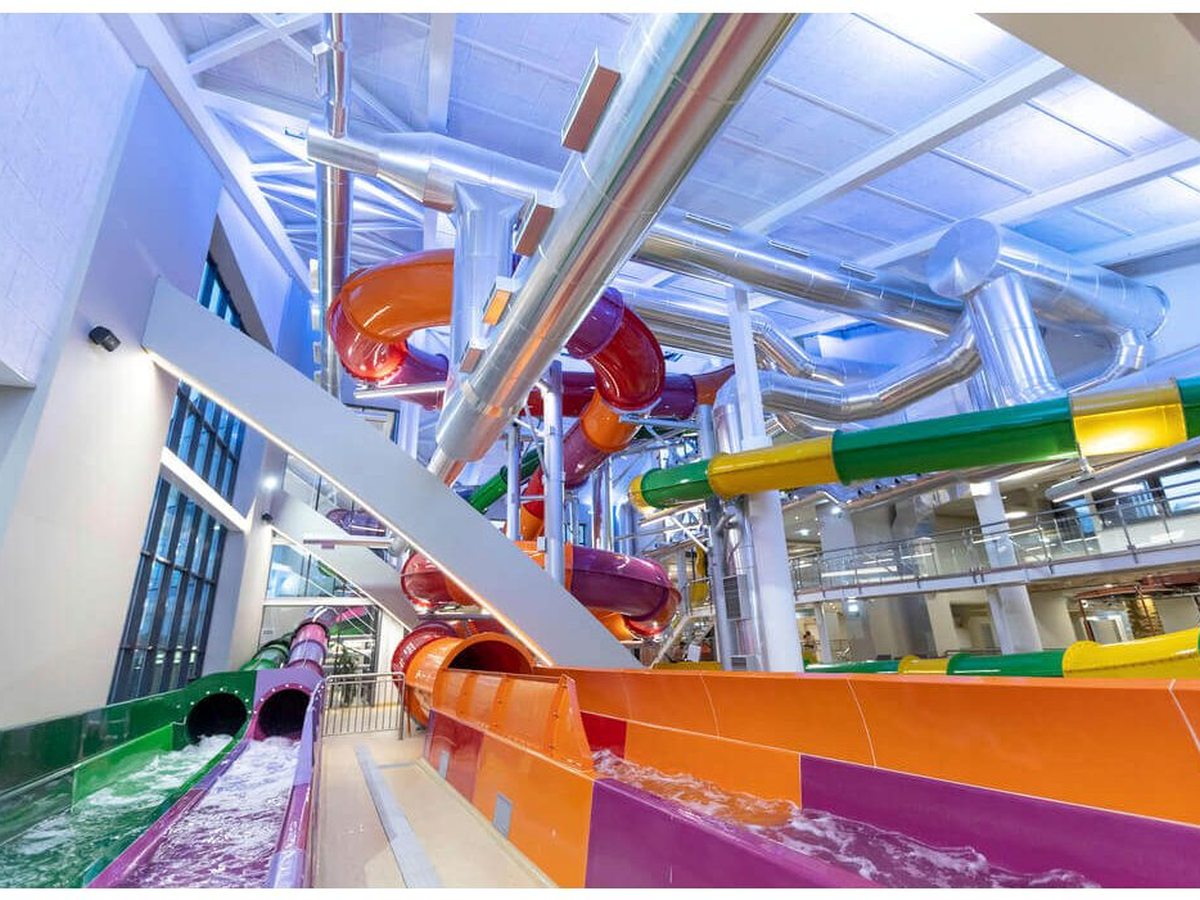 Multi-level indoor water slides in red, orange, purple and green on steel supports.