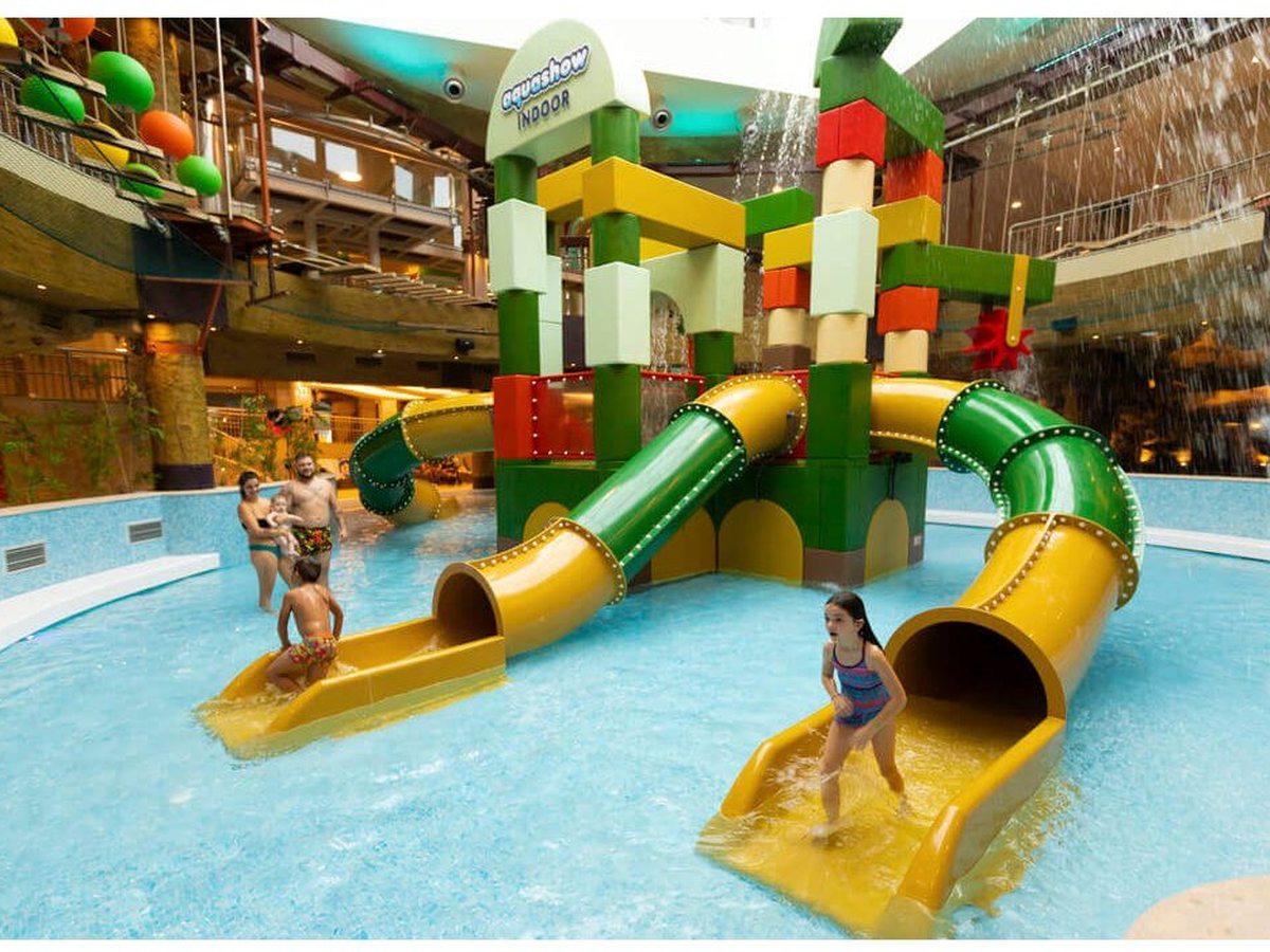 A shallow indoor splash pool with a colourful play tower and twin slides.