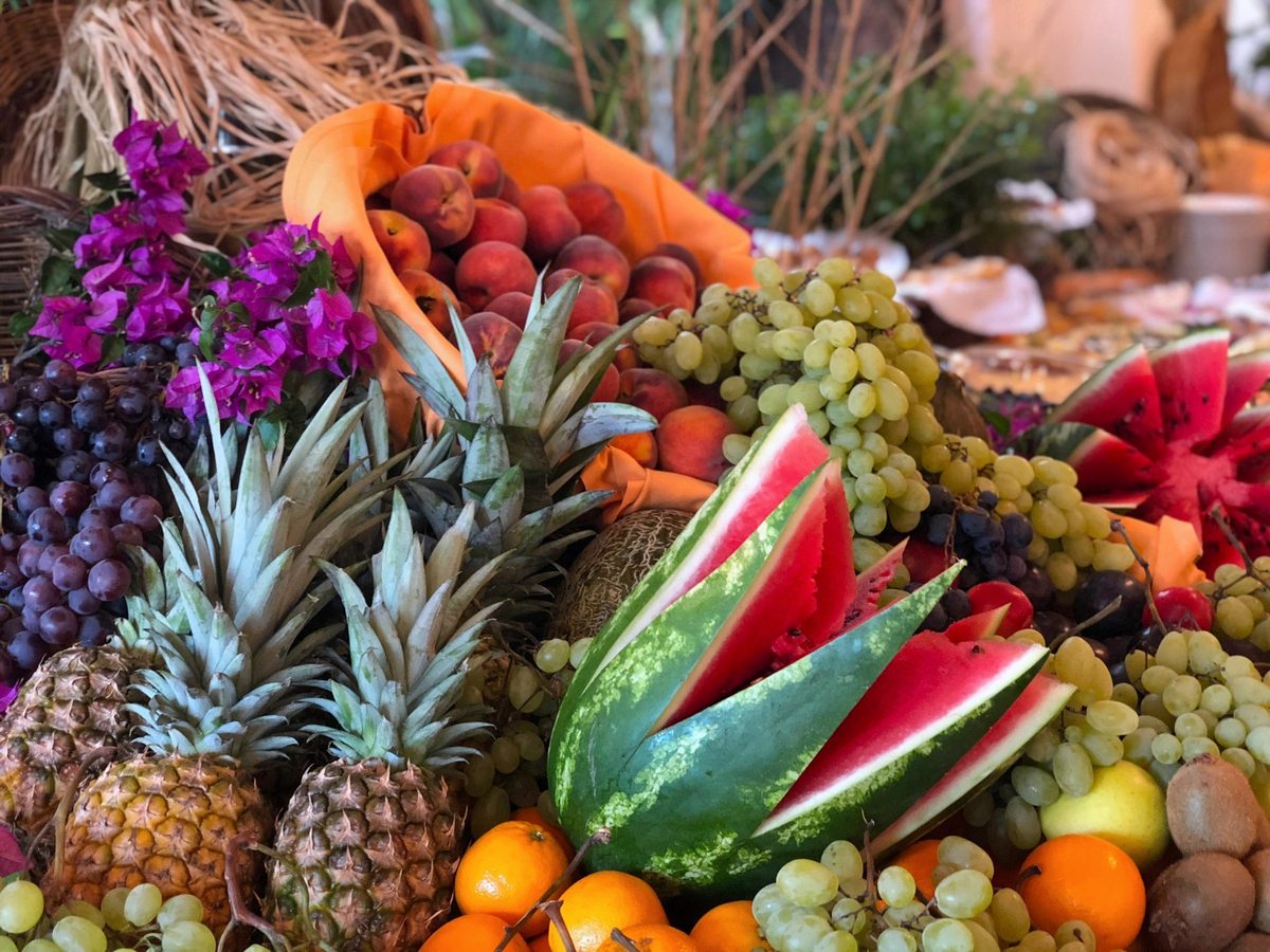 A buffet display piled with pineapple, watermelon, grapes, oranges and other fresh fruit.