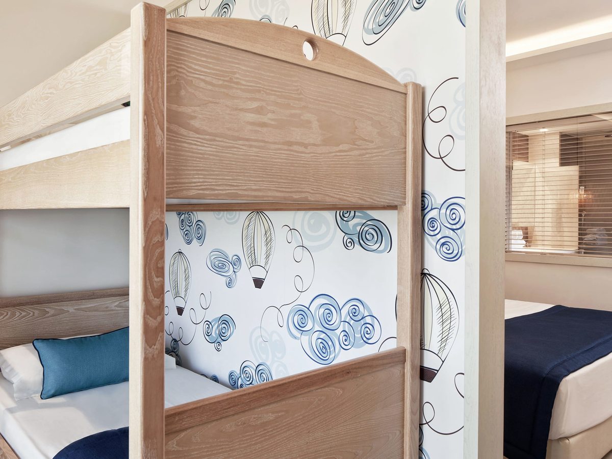 Wooden bunk beds with hot-air-balloon patterned wallpaper, and the main double bedroom visible through the doorway.