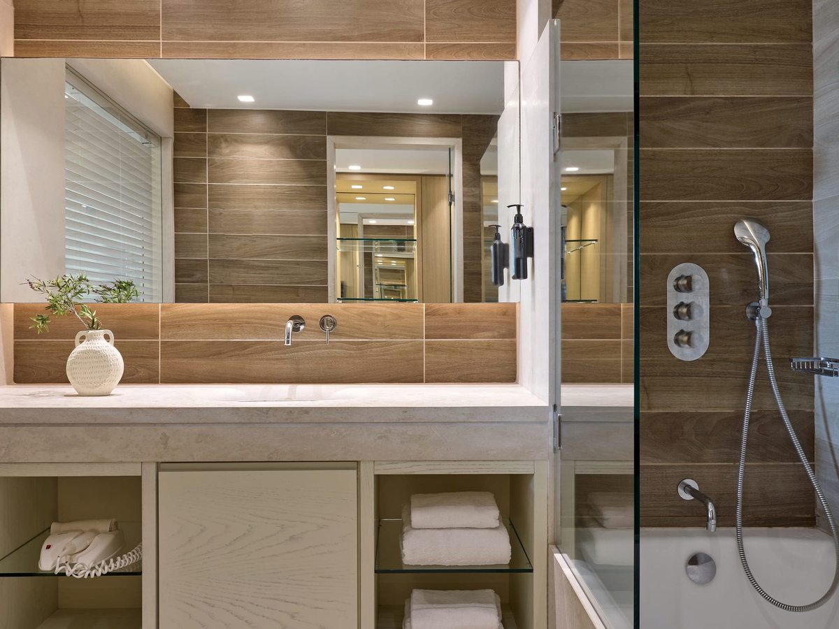 A bathroom with a wood-panelled walk-in shower, a vanity unit and a large mirror.