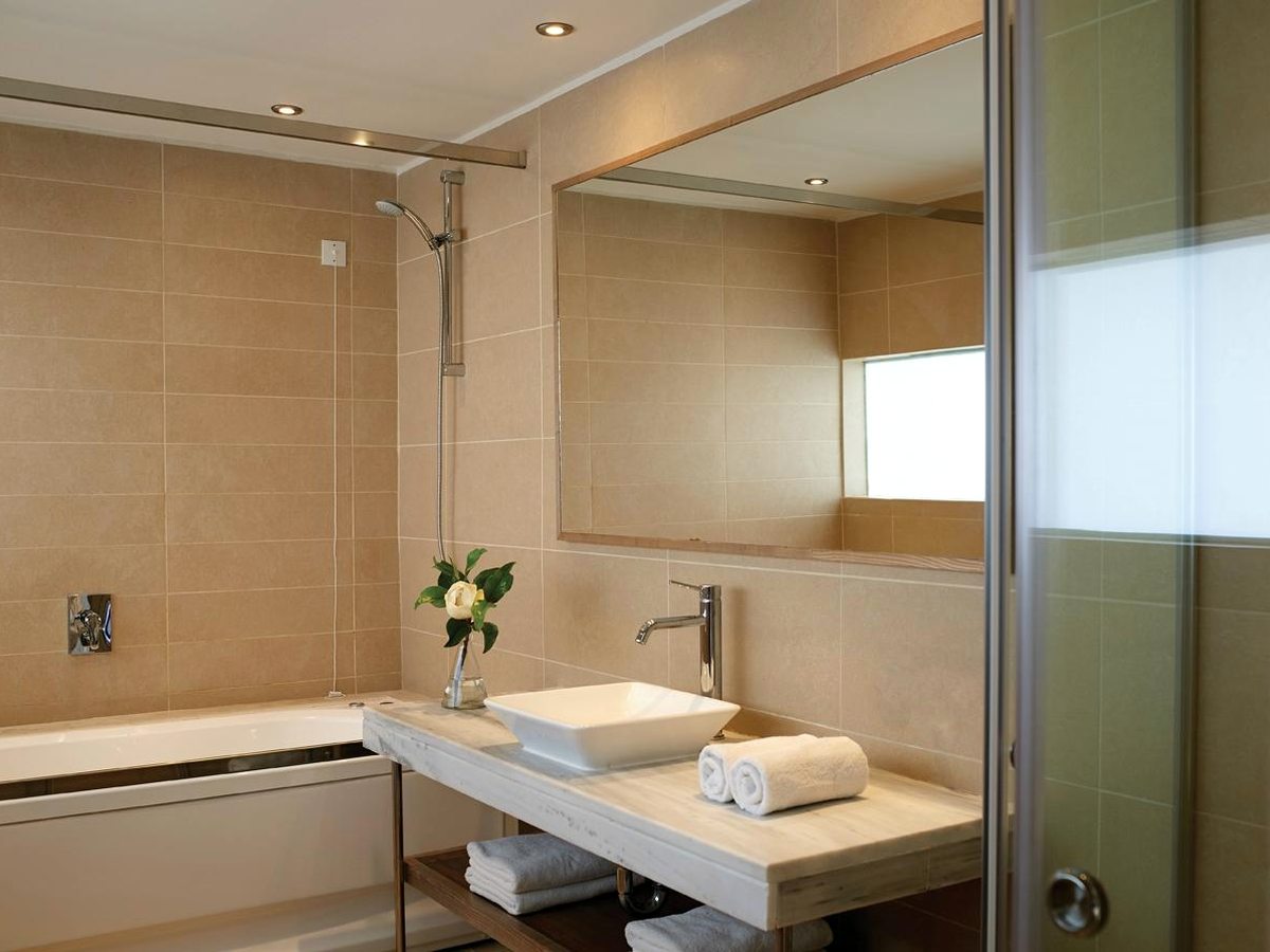 Bathroom with a bath, a vessel basin on a stone counter, a large mirror and a glass walk-in shower.