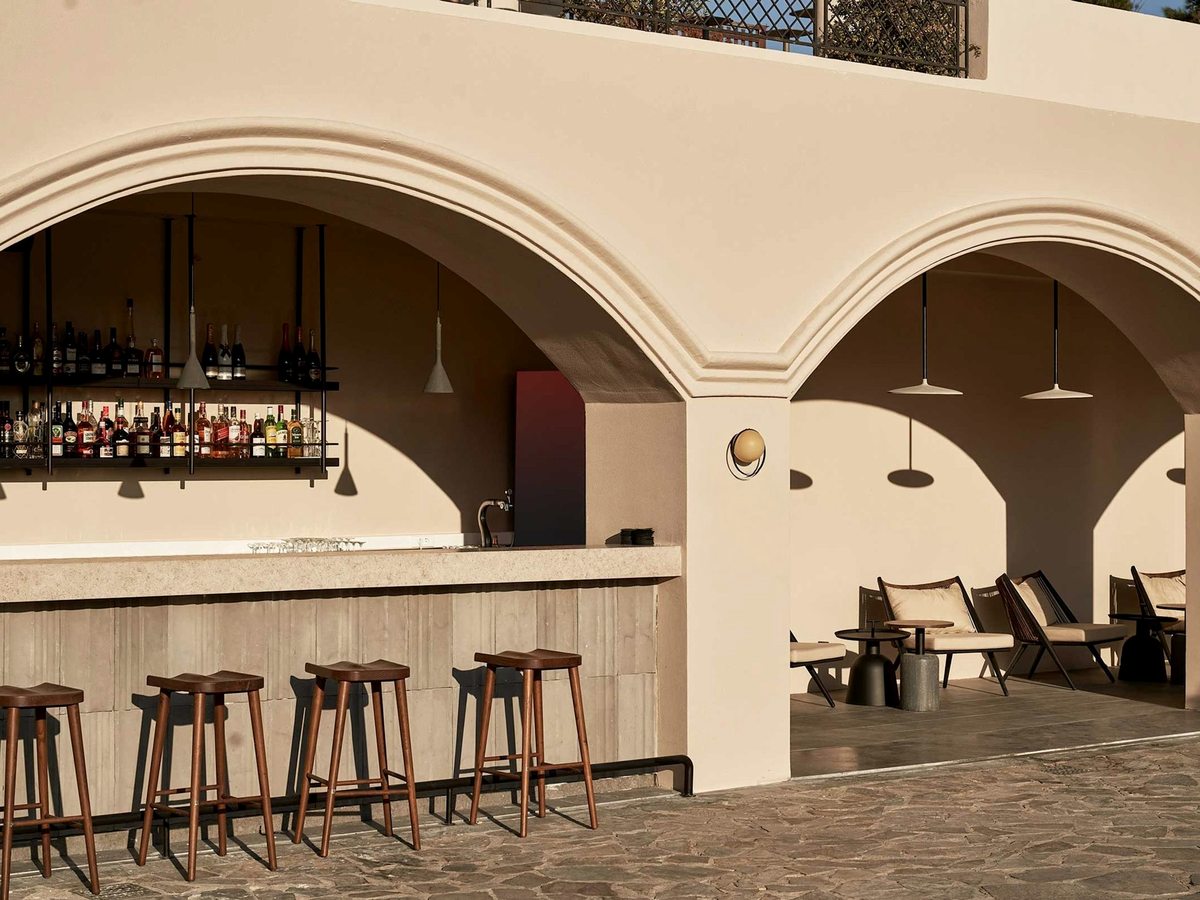 Bar under stone arches with a long counter, wooden stools and lounge seating.