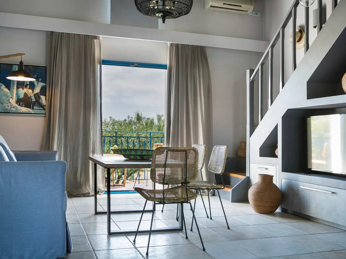Split-level maisonette with a living and dining area below and an internal staircase up to a mezzanine, with a balcony treetop view.
