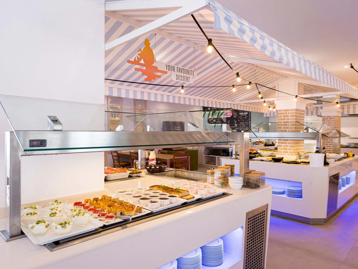 Self-service buffet counter with trays of cold dishes and desserts under a lit canopy in the main restaurant.