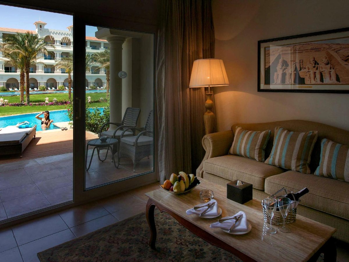 A suite lounge with a sofa and cushions, a coffee table and sliding glass doors onto a private terrace with a pool view.