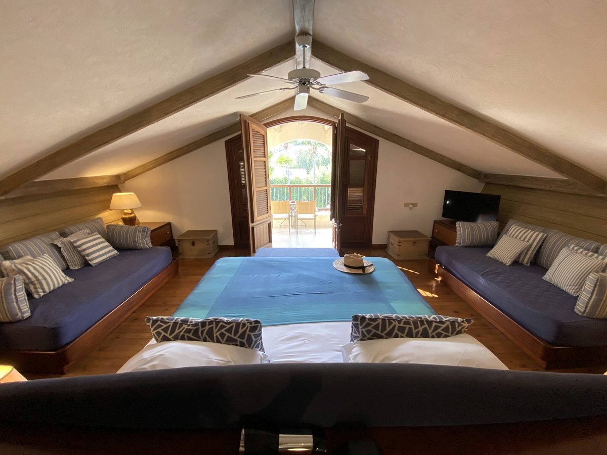 A top-floor suite under a pitched timber ceiling, with a double bed and two sofa beds on a wooden floor.