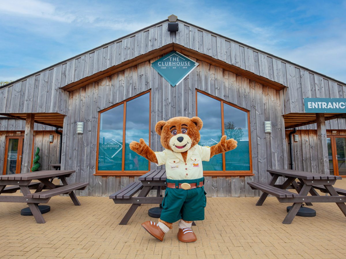 The timber Clubhouse building with picnic benches outside and the Crealy bear mascot by the entrance