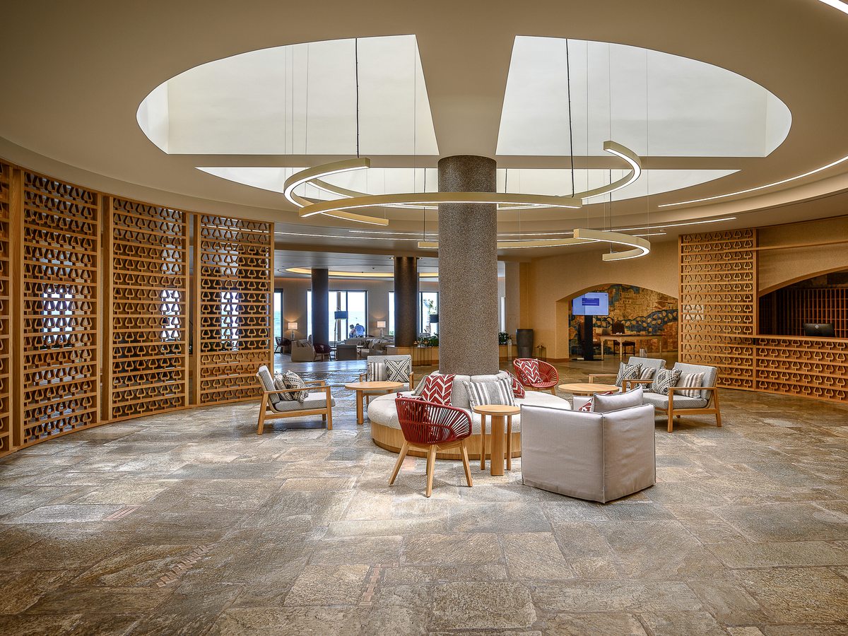 A circular open-plan hotel lobby with lounge chairs and sofas beneath a domed ceiling and central column