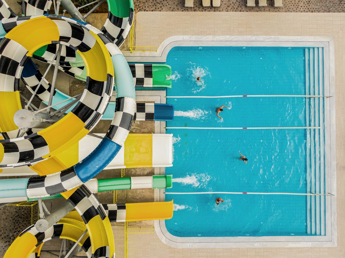Aerial view of the waterpark's coiled yellow, green and chequered slides beside a rectangular activity pool with swimmers