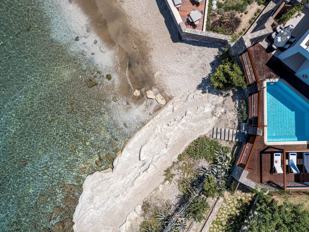 Aerial view of a rocky, low-lying shoreline beside the bungalows, with a small private pool and deck at the water's edge