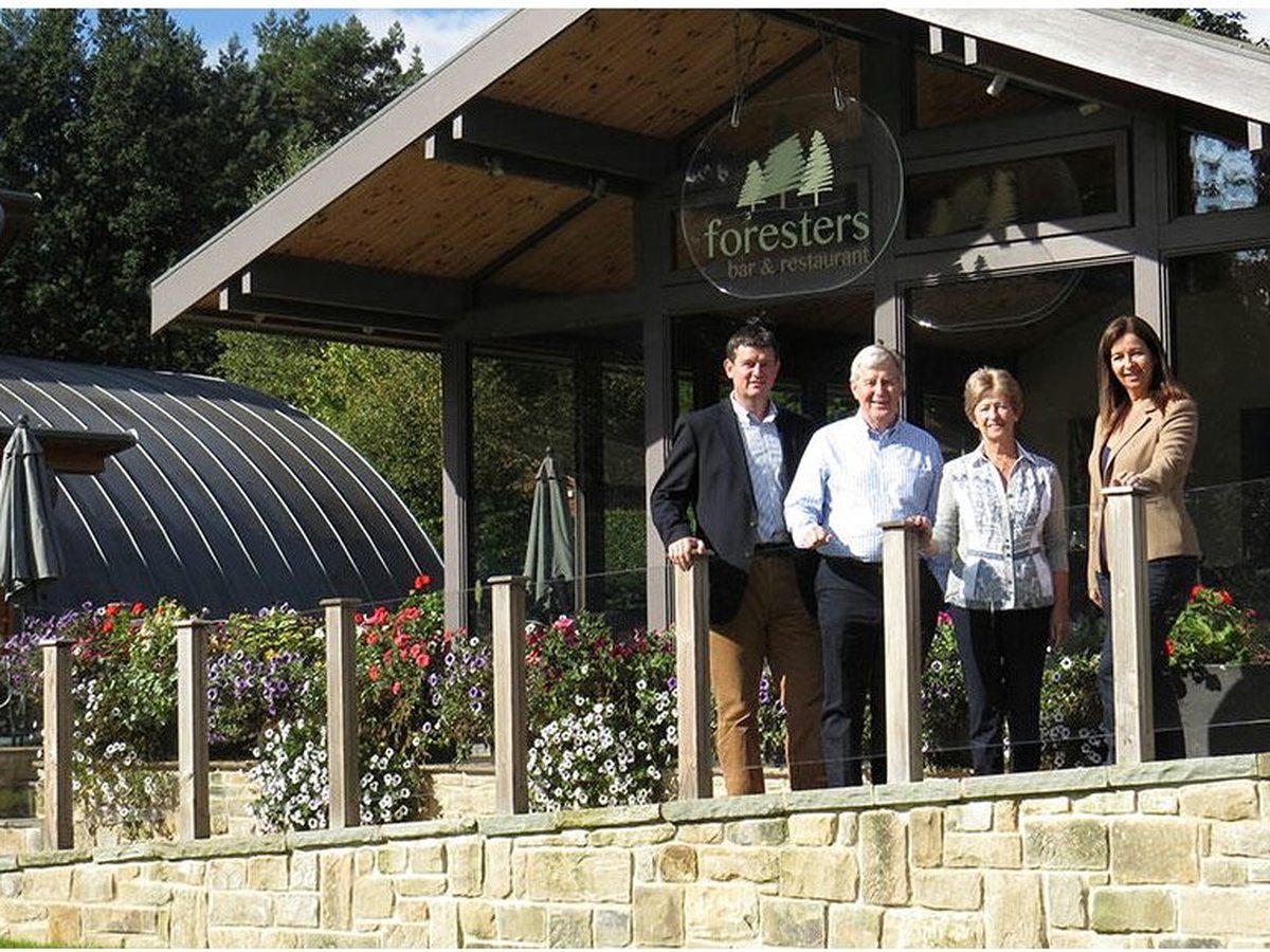 The Foresters, a timber bar and restaurant with a covered terrace and outdoor seating, set among trees.