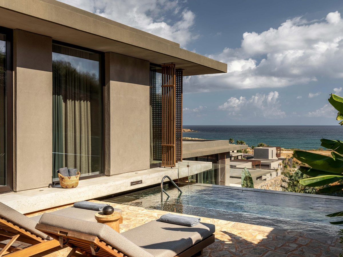 A small stone-edged plunge pool on a terrace beside a suite, looking out over the resort rooftops to the sea.