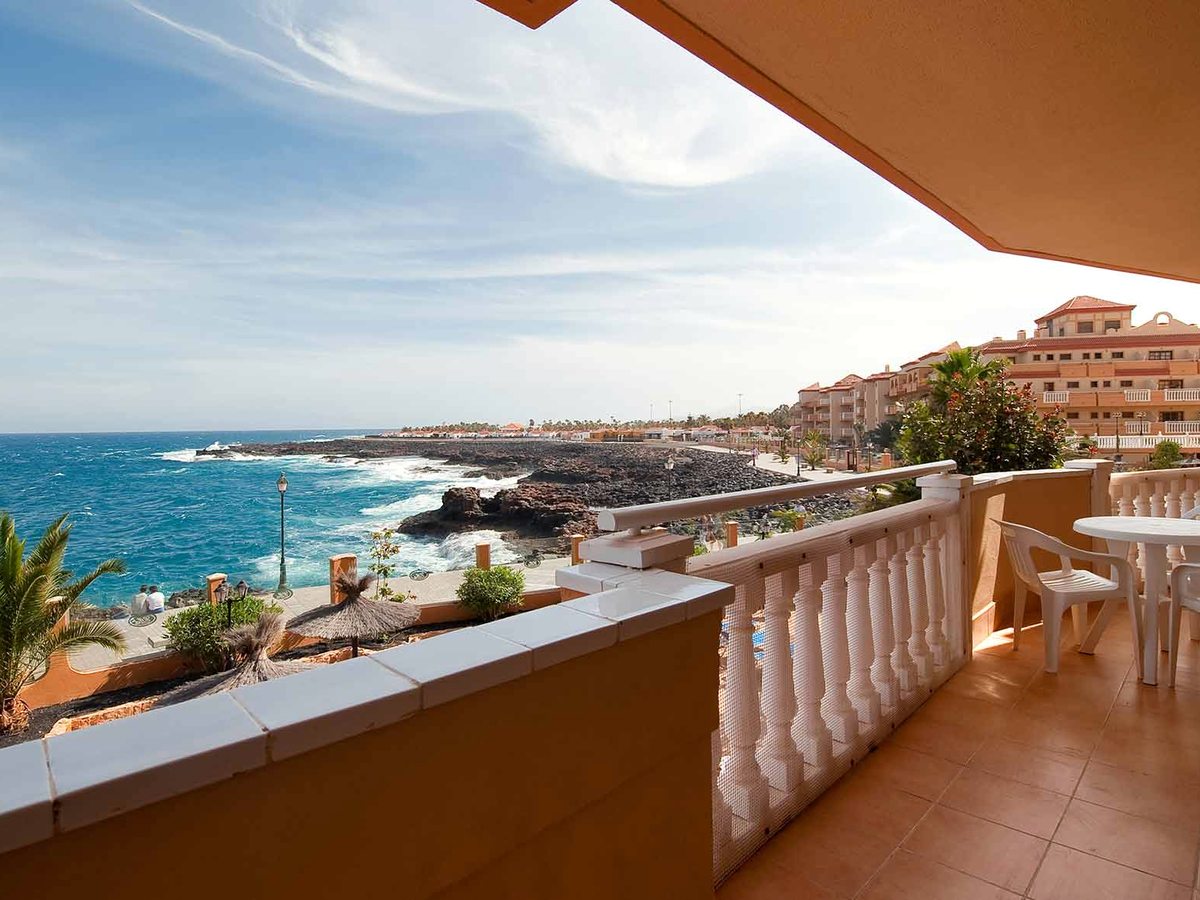 A room balcony with a white balustrade looking out over the rocky coastline and the ocean.