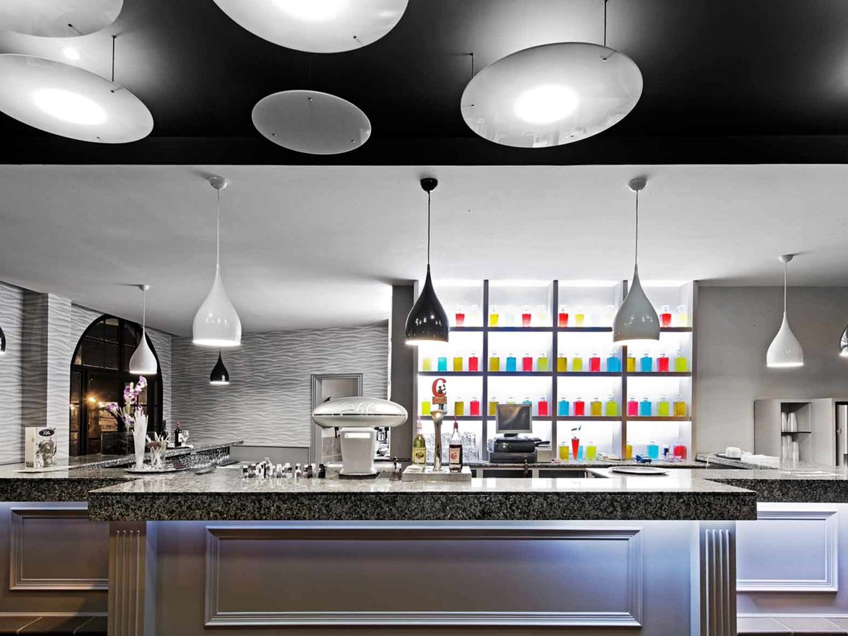 A bar with a stone counter, pendant lights and backlit shelves of colourful bottles.