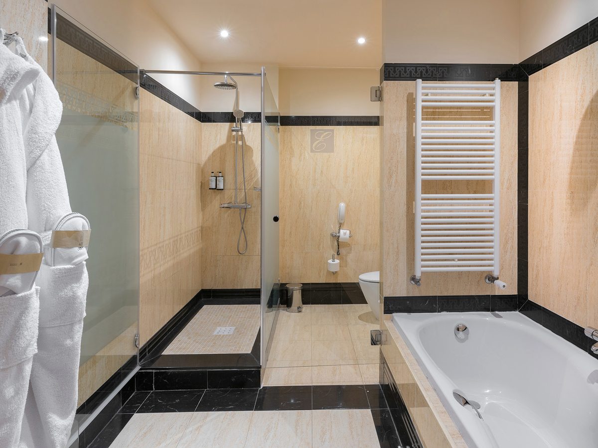 A bathroom with a bathtub alongside a separate glass shower enclosure, a heated towel rail and a bathrobe.