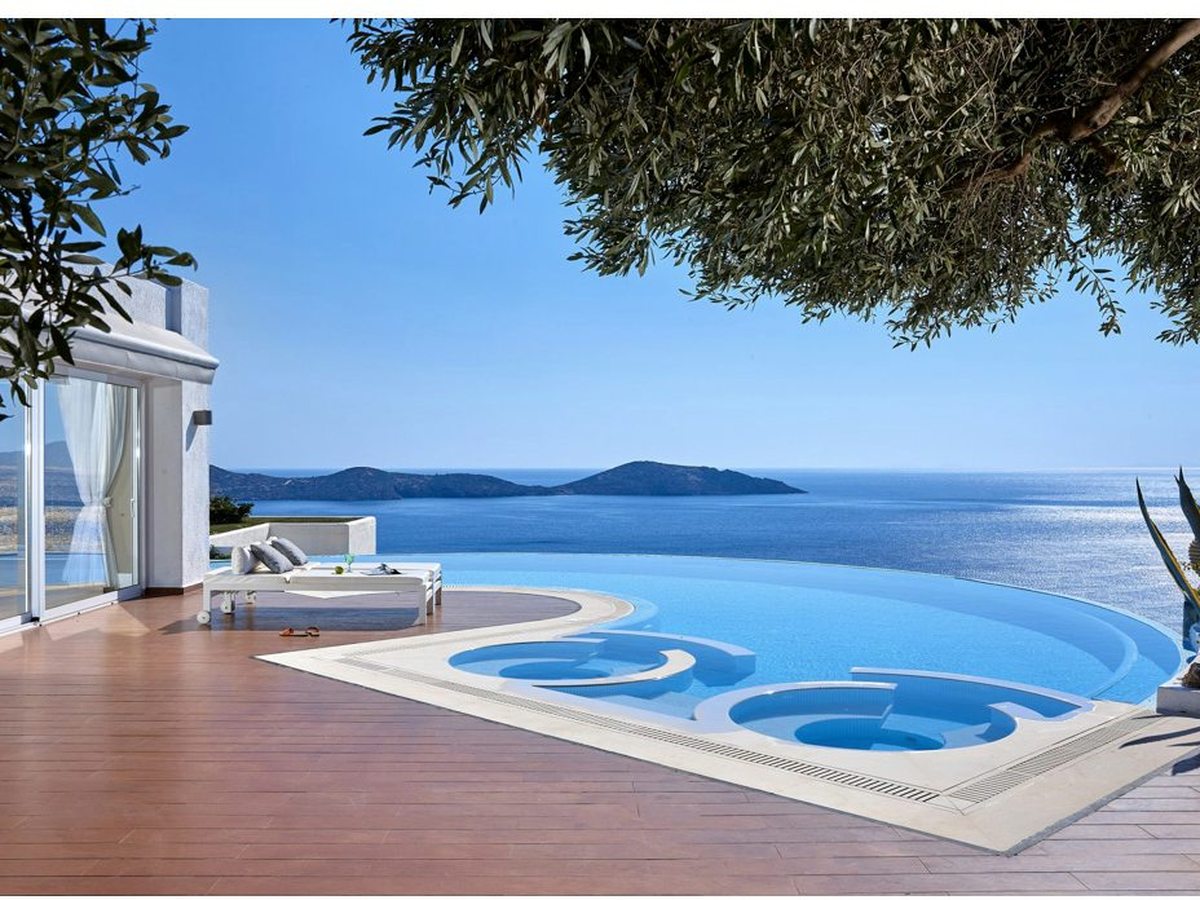 Villa infinity pool with a sunken circular Jacuzzi set into the deck, framed by an olive tree, with the gulf and an island beyond.