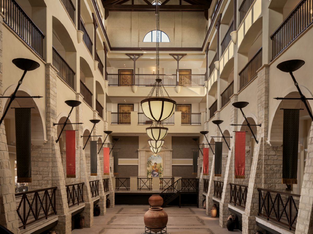 A tall internal atrium rising several floors, with stone arches, balconies, hanging lanterns and red banners.